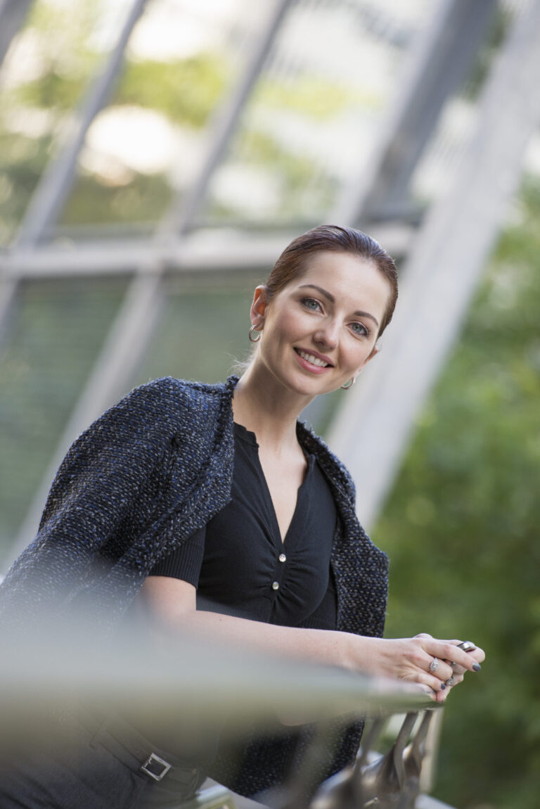 New York City outdoors business shoot,USA,Business people outdoors, keeping in touch while on the go. A woman in a grey jacket with her hair up, leaning on a railing