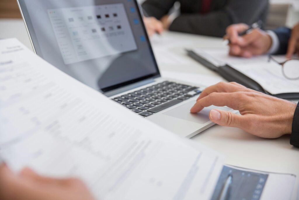 a person looking at a paper while using a laptop