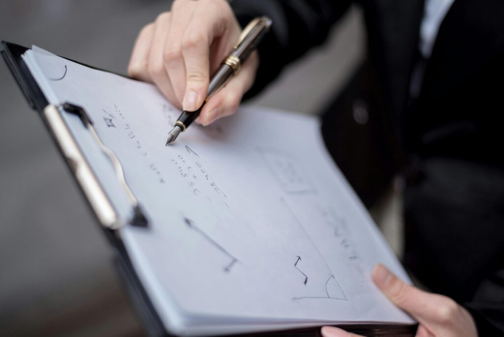 a person writing on a paper in a clipboard