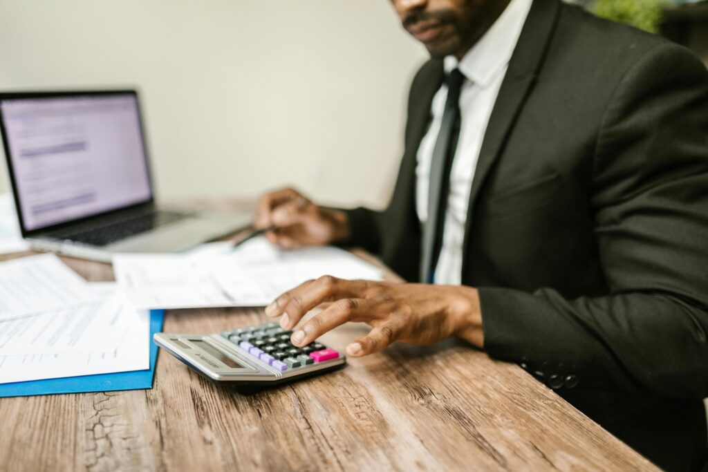 a man sitting on a table using calculator and computer