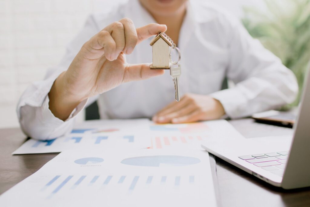 a man in white long sleeve shirt holding a house keychain with a key